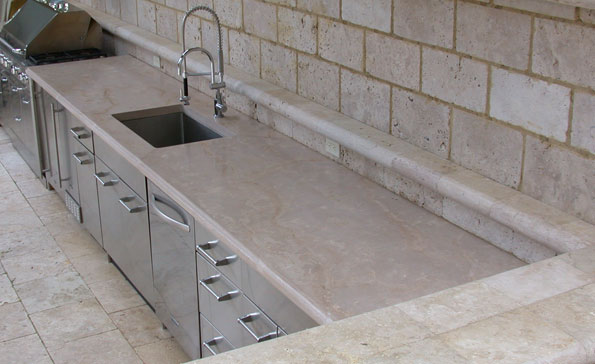 Outdoor concrete kitchen counter made of cast concrete whichmatches the travertine walls and deck.