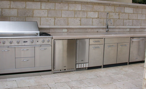 Outdoor concrete kitchen counter made of cast concrete whichmatches the travertine walls and deck.