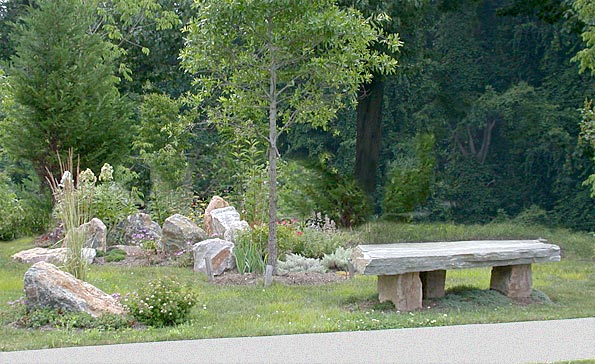 A contemplation bench made of rock slabs with a grouping of coordinating regional stone boulders.